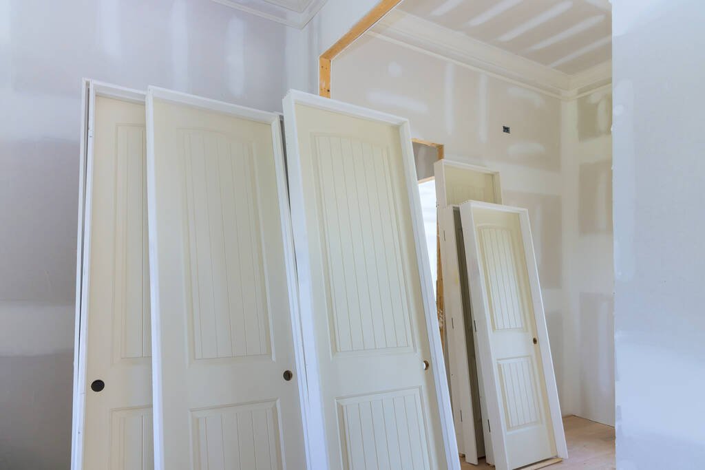varias puertas blancas apoyadas en pared en obra en construccion - puertas SEMYC Puebla